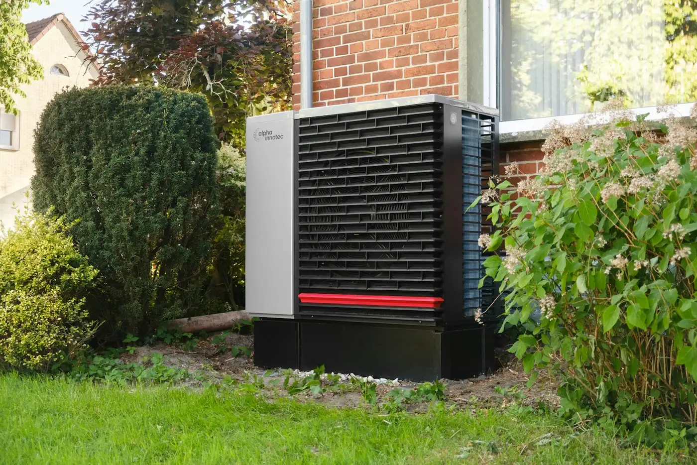 Buitenunit van een warmtepomp naast een bakstenen huis
